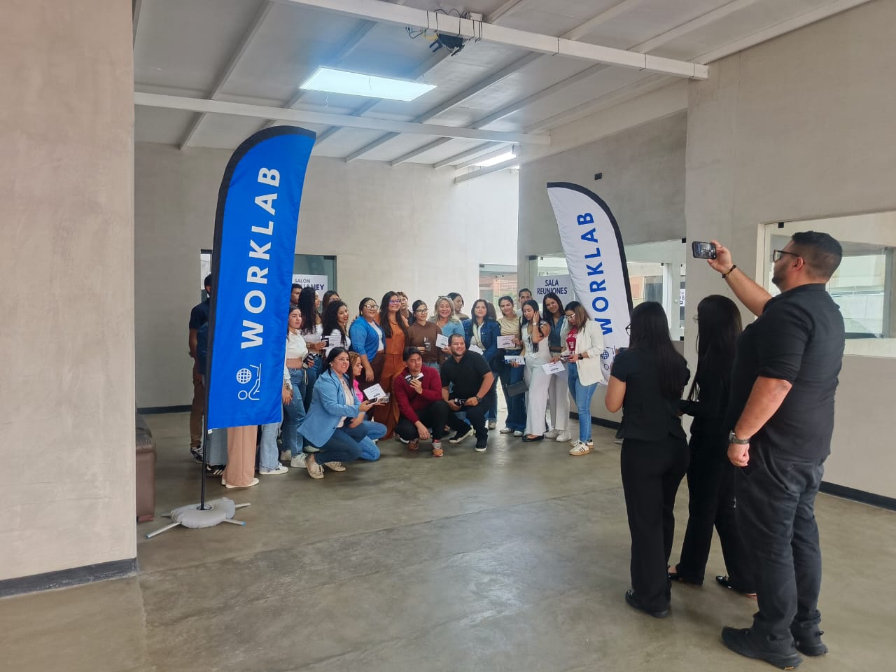 Grupo de graduados posando con banners WORKLAB tras una formación