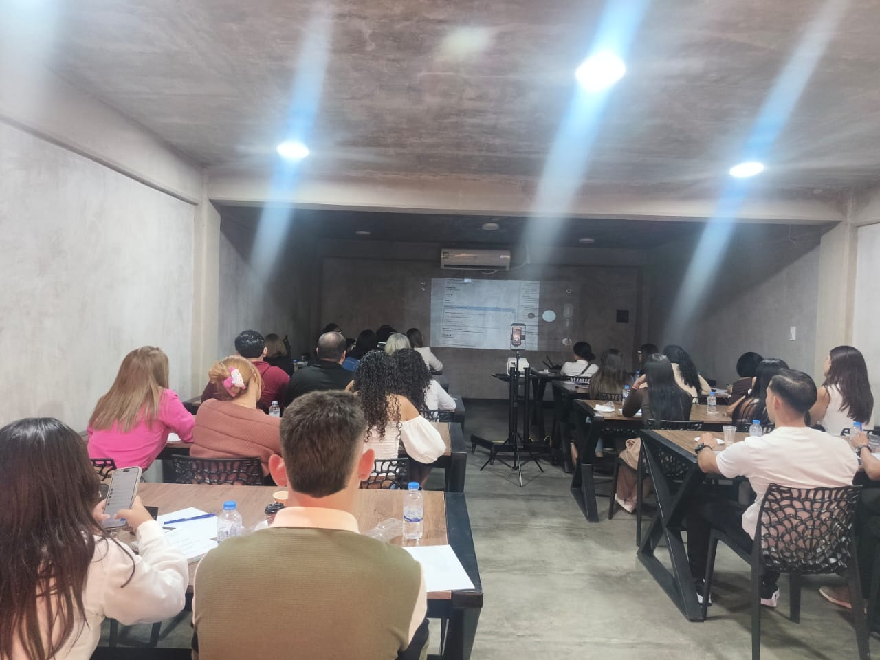 Salón de cursos con participantes y proyector encendido en WORKLAB